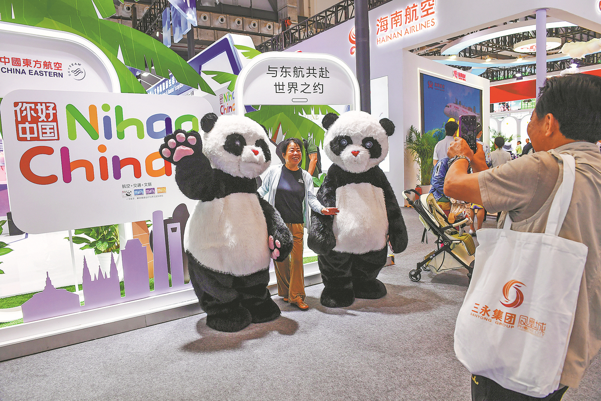A visitor takes pictures with panda mascots during the 2025 China International Travel Mart in Haikou, Hainan province, on Dec 20. YUAN JINGZHI/FOR CHINA DAILY