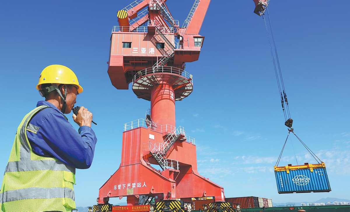 An employee arranges to load the first batch of offshore goods onto a ship at Sanya Port in Sanya, Hainan province, on Dec 18. LI XUESHI/FOR CHINA DAILY